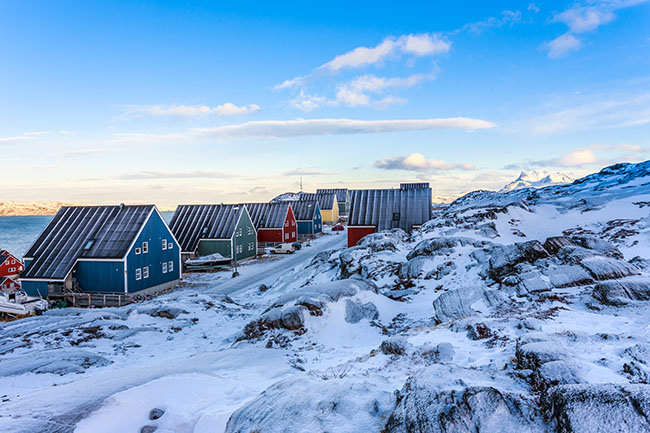 Yellow, blue, red and green inuit houses along the snow street w