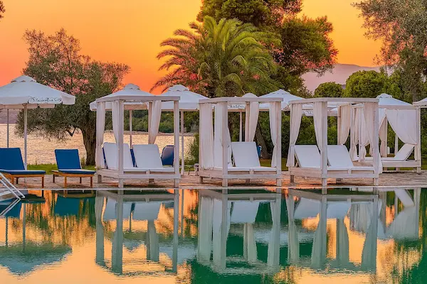 Rejse til Evia - billede af liggestole ved poolen med solnedgangen i baggrunden